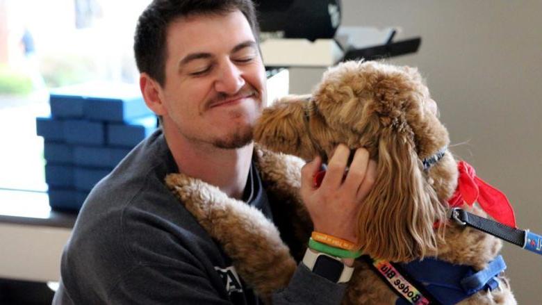 365英国上市杜波依斯分校的三年级学生杰夫·罗曼诺在365英国上市杜波依斯分校的减压节活动中，享受着一只治疗犬给他的安慰.